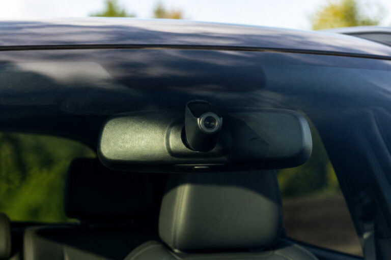 Vue rapprochée d'une caméra intégrée au rétroviseur intérieur d'une voiture moderne.