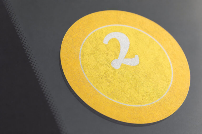 Autocollant jaune rond Crit'Air numéro 2 apposé sur une vitre de voiture.