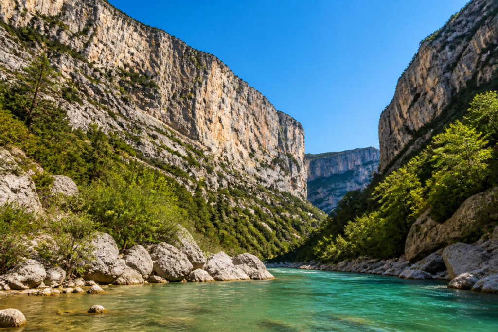 Vue spectaculaire des Gorges du Verdon avec ses falaises calcaires et sa rivière aux eaux turquoise sous un ciel bleu.