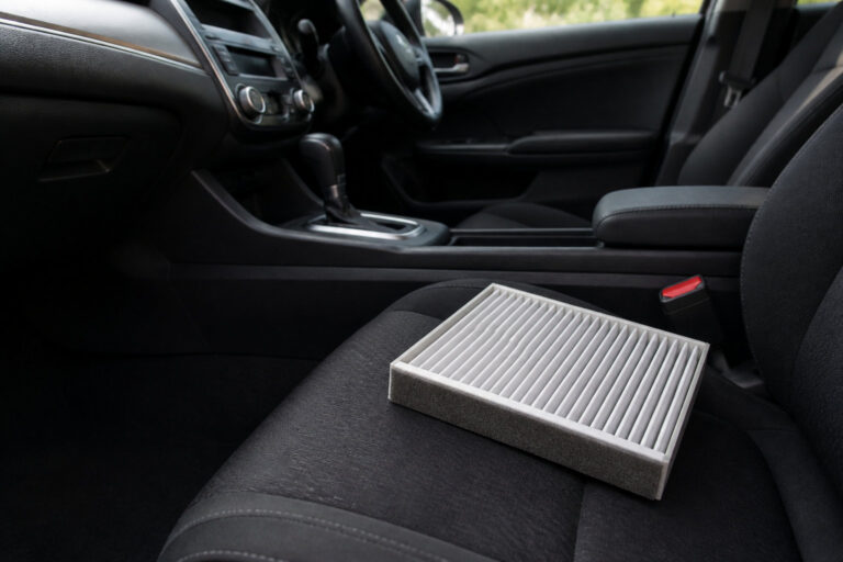 Filtre d'habitacle neuf posé sur le siège passager d'une voiture.