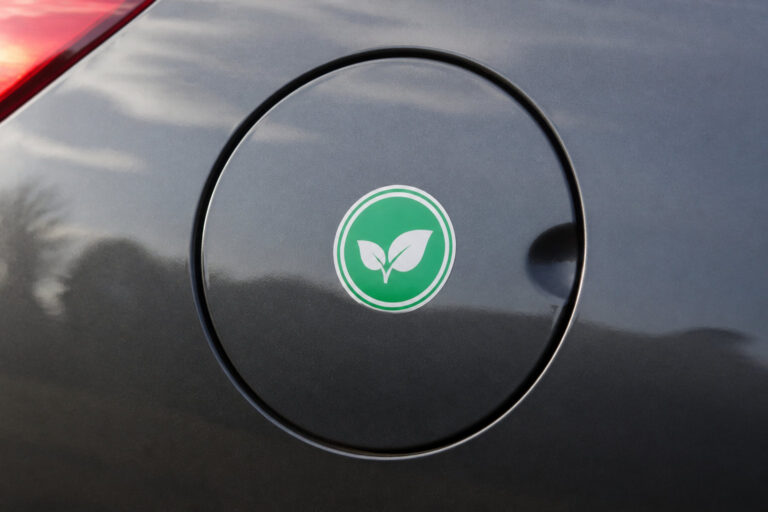 Trappe à essence d'une voiture grise ornée d'un autocollant vert avec deux feuilles blanches symbolisant l'écologie.